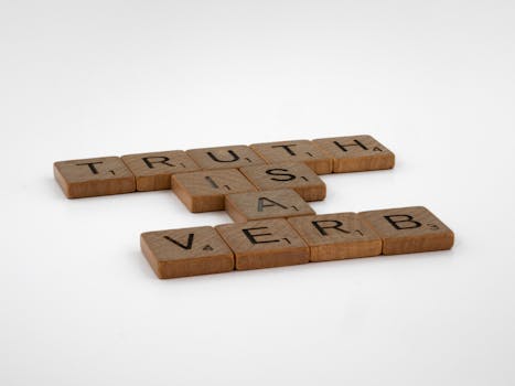 pexels-photo-9540541-9540541 Close-up of wooden Scrabble tiles on a white surface spelling out 'Truth is a Verb'.